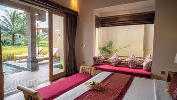 Habitación de hotel con una cama grande, una cama más pequeña, vista a un jardín y un balcón con piscina.