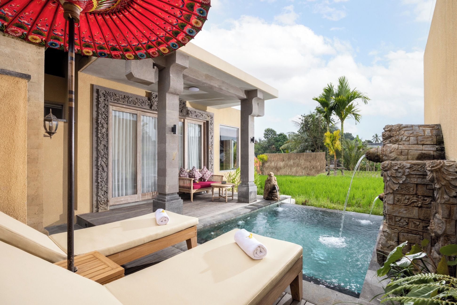 Zona de piscina con sillones de descanso, una mesa y un parasol decorativo.