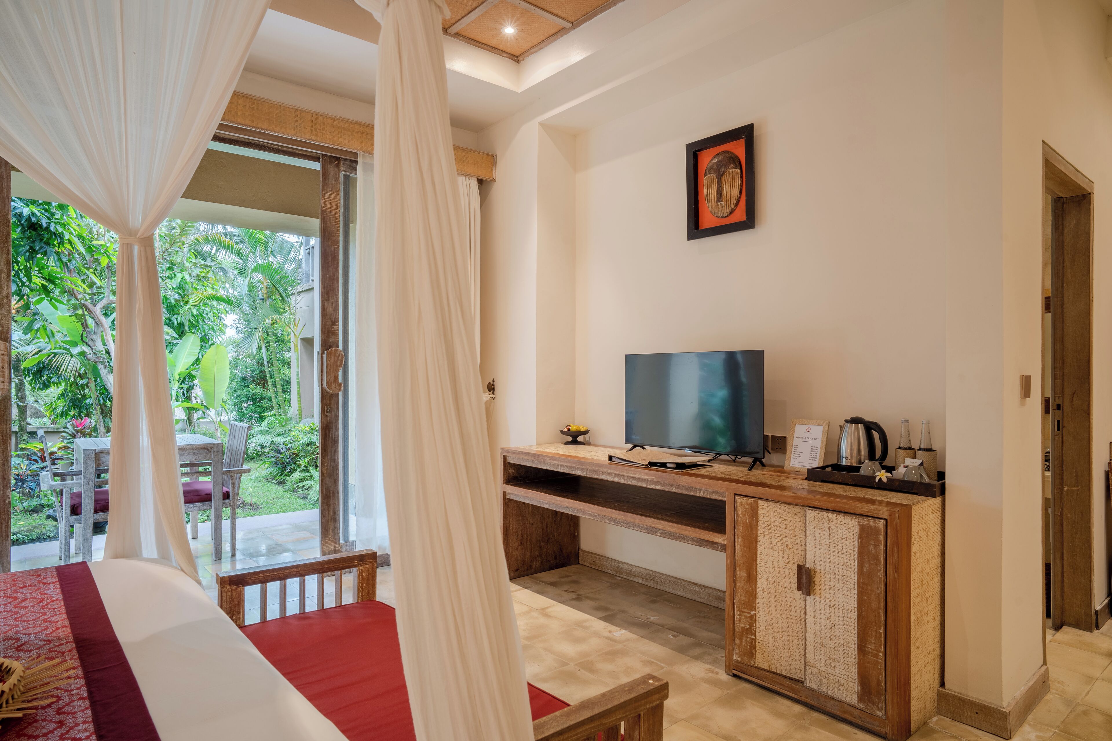 Ein Zimmer mit Bett, Fernseher, Holzschrank und einem Balkon mit Blick auf Grünflächen.