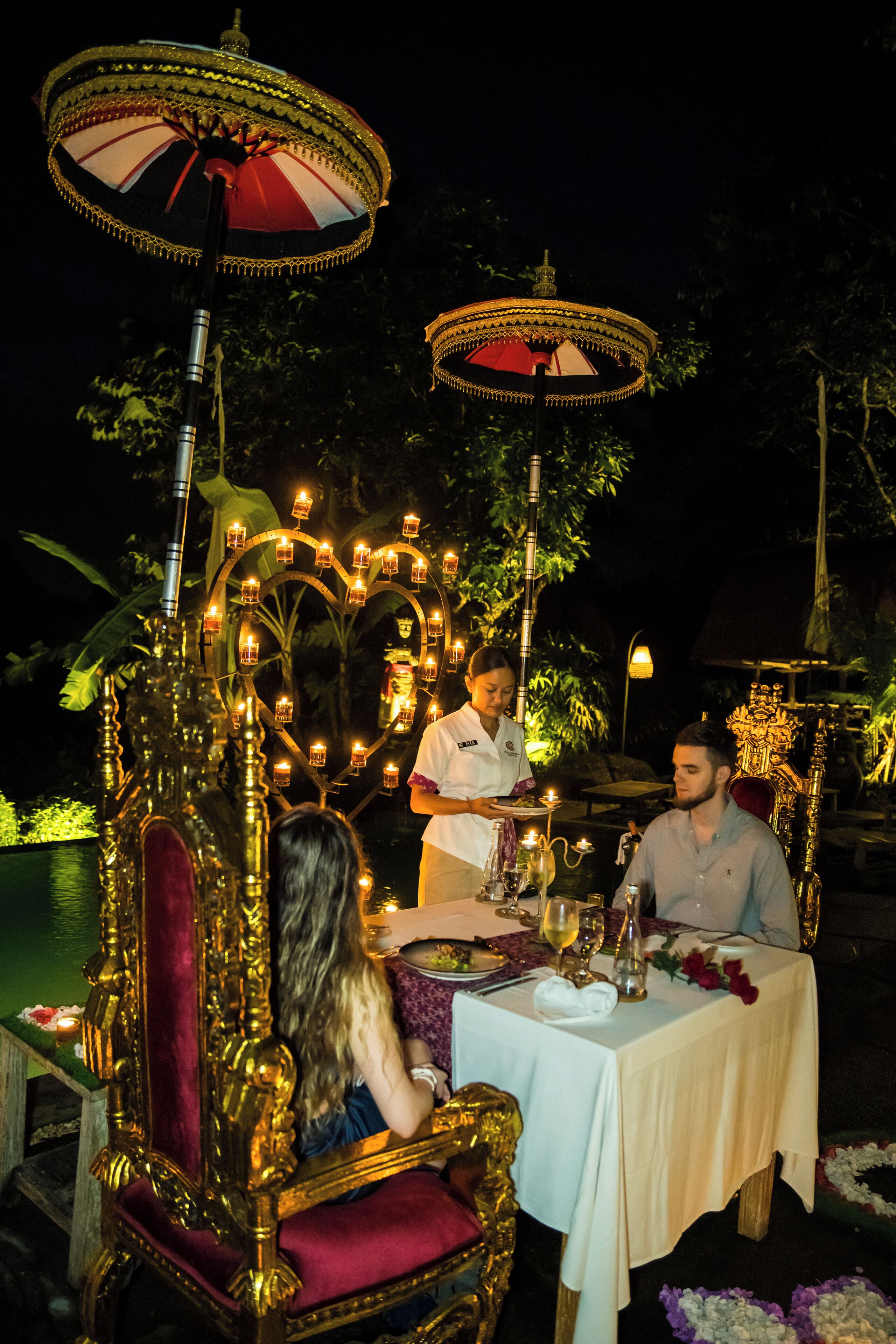 Un espace de restauration extérieur luxueux, agrémenté de chaises et de tables dorées richement décorées, illuminé par des jeux de lumière décoratifs.
