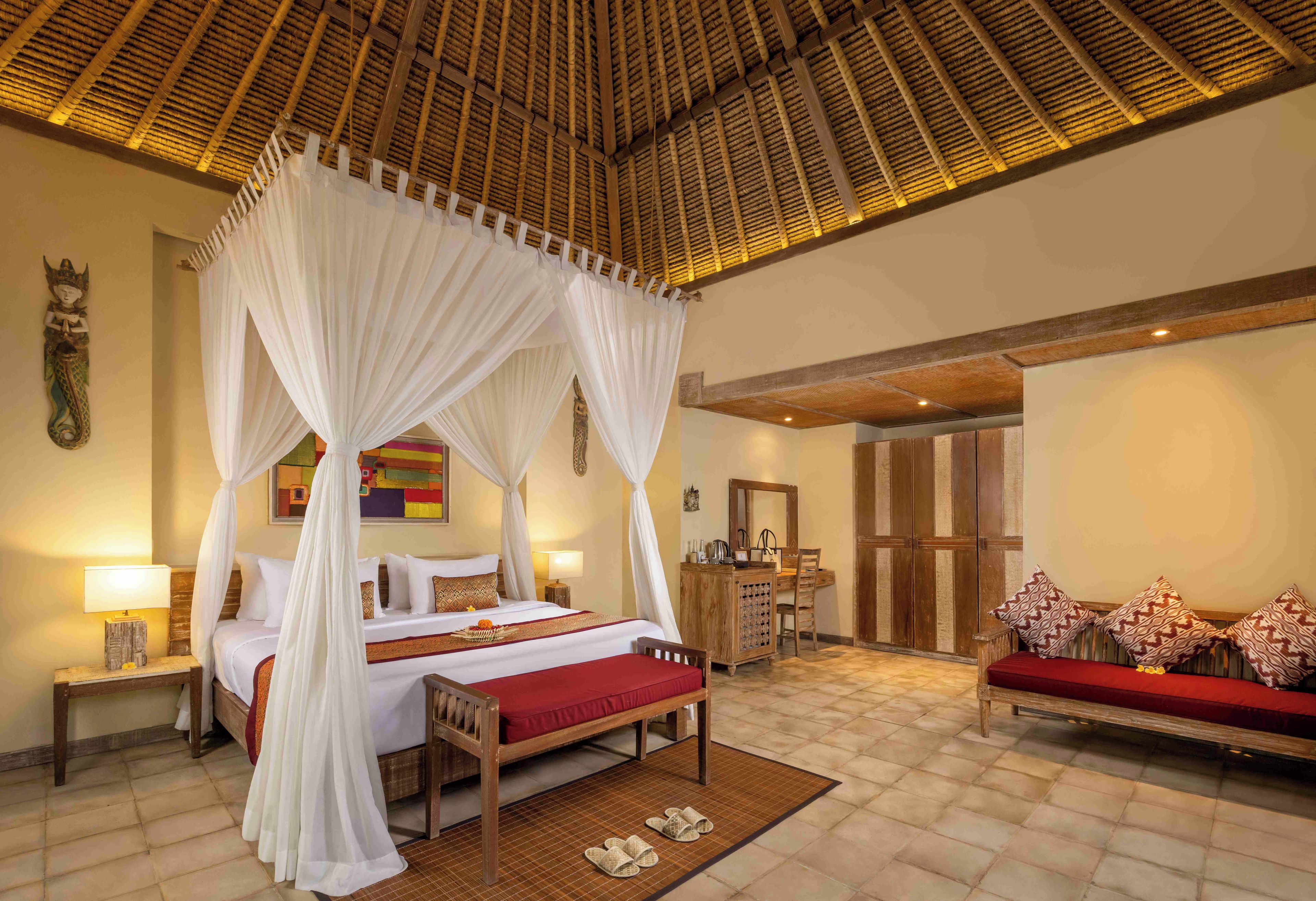 A room with a four-poster bed, a wooden desk, a sofa, and a large mirror.