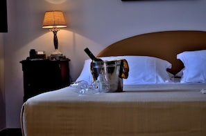 A neatly made bed with white linens, a bedside lamp, a small table with a lamp, and a glass jar with a straw. - Casale del Murgese (Fasano)