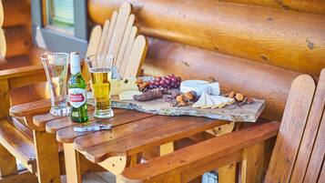 Un banco de madera con una tabla de quesos, vasos y una botella de cerveza.