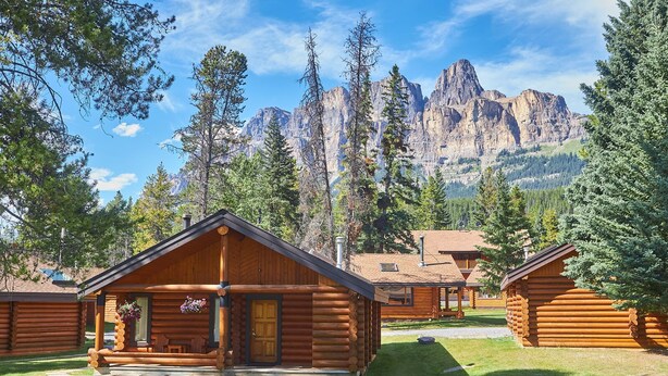 A row of log cabins with a mountain backdrop. - Castle Mountain Chalets (Castle Junction)