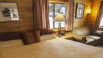 Una habitación acogedora con una cama grande, un sofá pequeño, una lámpara y cuadros en las paredes.