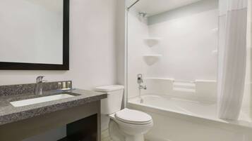 Une salle de bain moderne avec un lavabo en granit, des toilettes et une baignoire.