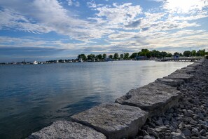 A waterfront with a stone pier, calm water, and boats.