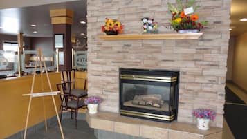 A lobby with a stone fireplace, a reception desk, and a wooden ladder.