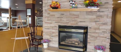 Un vestíbulo con chimenea de piedra, un mostrador de recepción y una escalera de madera.