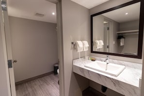 Un baño moderno con un lavamanos blanco, un espejo grande y un perchero para toallas.