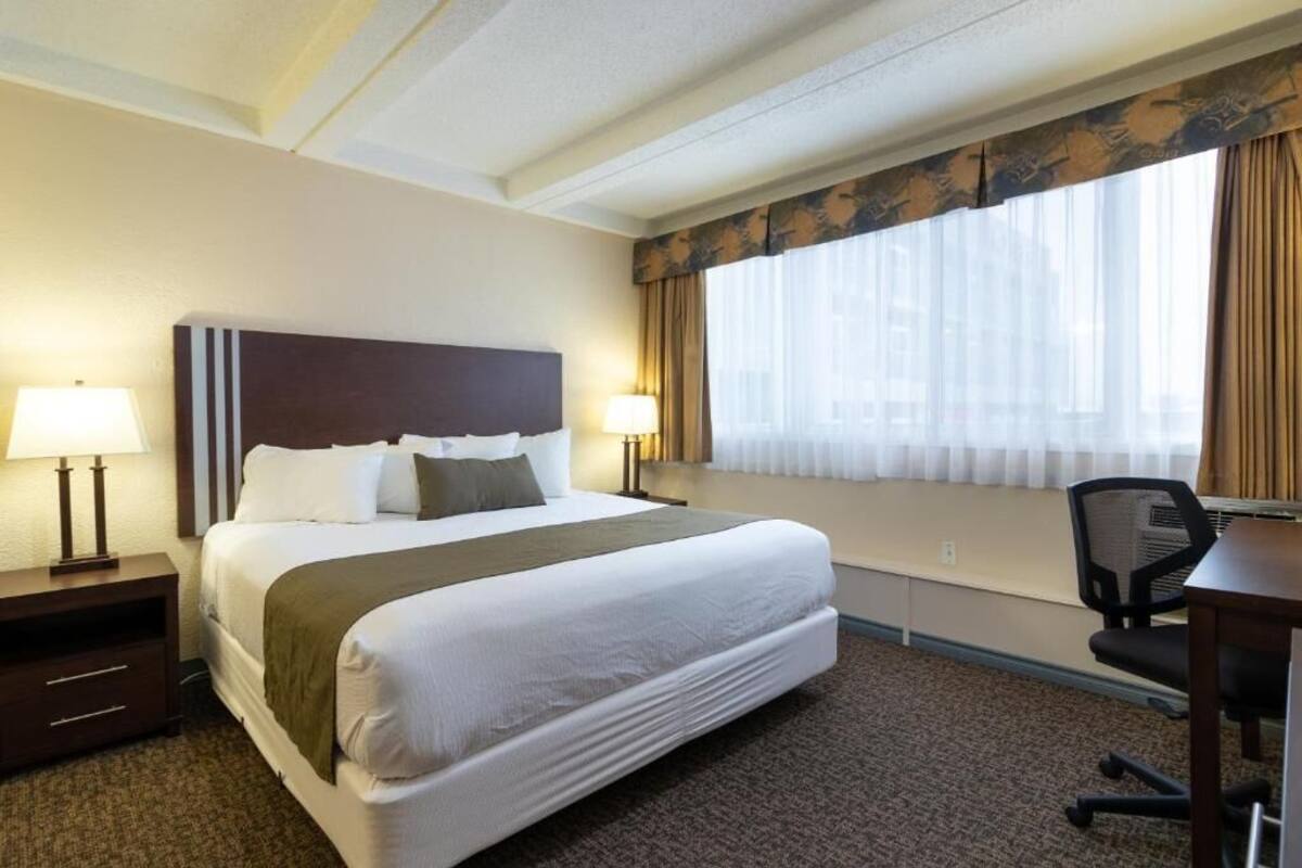 Una habitación de hotel con una cama grande, dos lámparas de noche, un escritorio y una silla.