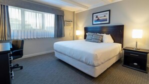 A hotel room with a large bed, a desk, and a chair. - BCMInns Fort McMurray (Fort McMurray)