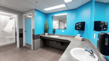 Un baño moderno con una pared azul de acento, un lavabo blanco, un espejo y dos dispensadores de toallas de papel.