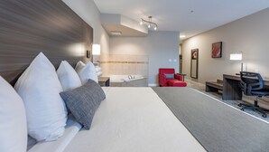 Ein Hotelzimmer mit einem großen Bett, einem Schreibtisch, einem Stuhl, einem roten Sessel, einem kleinen Tisch und einem an der Wand befestigten Fernseher.