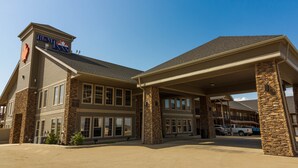 A hotel with a stone facade, a covered entrance, and a clear blue sky. - BCMInns Lac La Biche (Lac La Biche)
