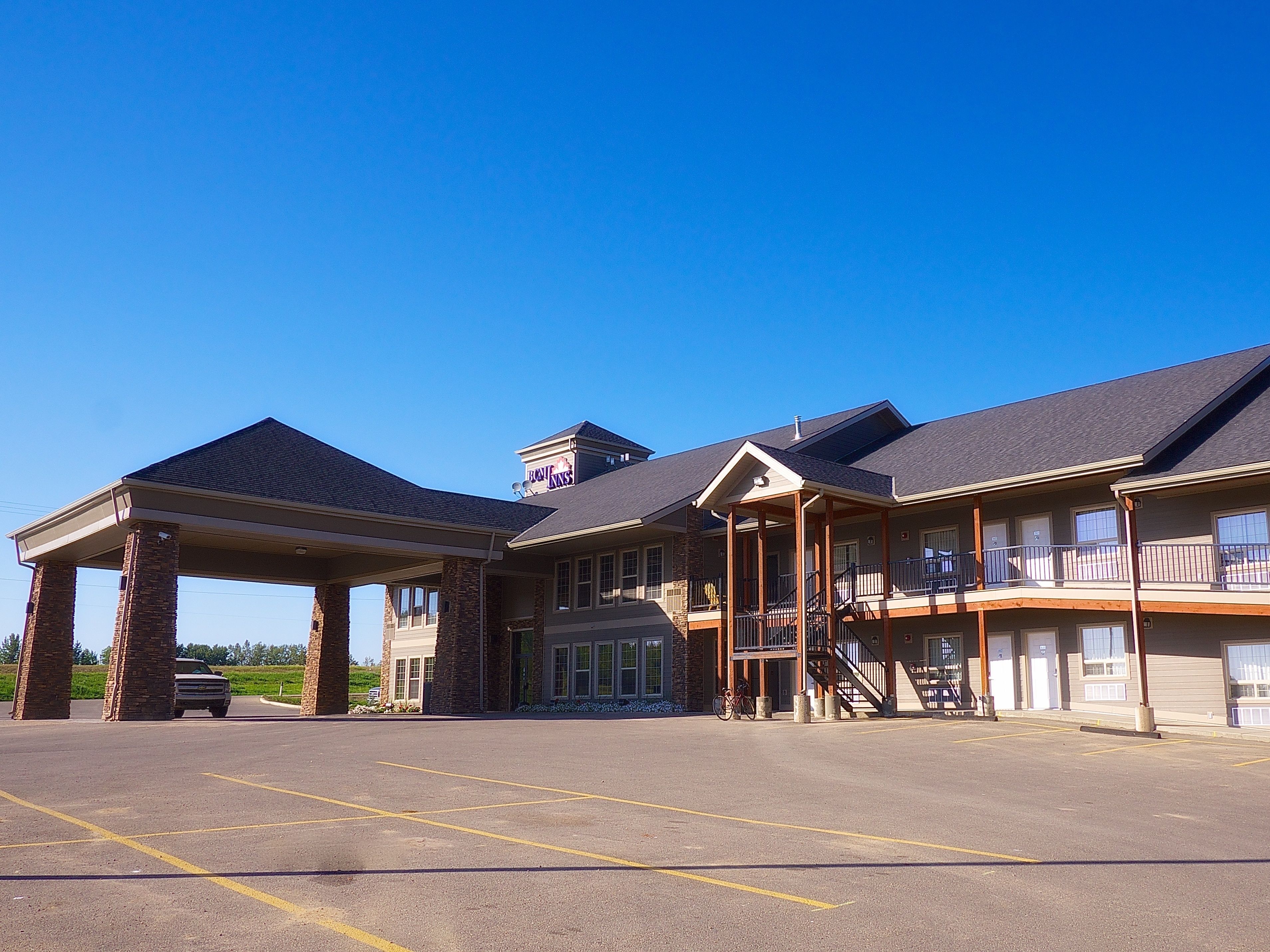 A hotel with a covered entrance, multiple balconies, and a parking lot.
