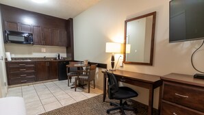 A compact hotel room with a kitchenette, a dining area, a desk, and a bed. - BCMInns Lac La Biche (Lac La Biche)