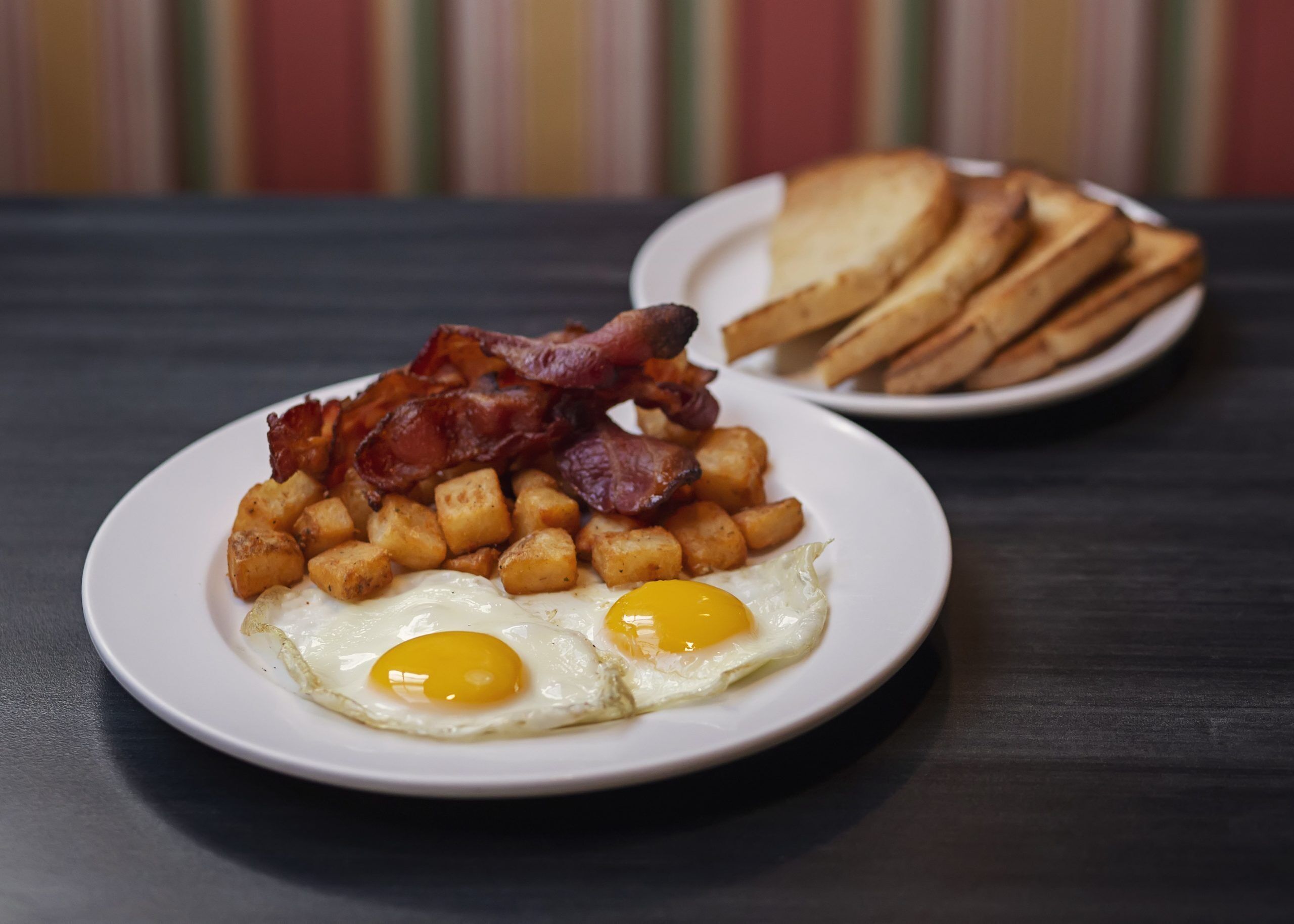 A plate of breakfast food including eggs, bacon, and hash browns.