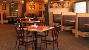 Interior de un restaurante con cabinas y mesas, un letrero que dice 'CAFE' y un letrero que dice 'Rusty's'.