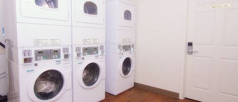 A laundry room with stacked front-loading washing machines and a door marked "EMPLOYEES ONLY".