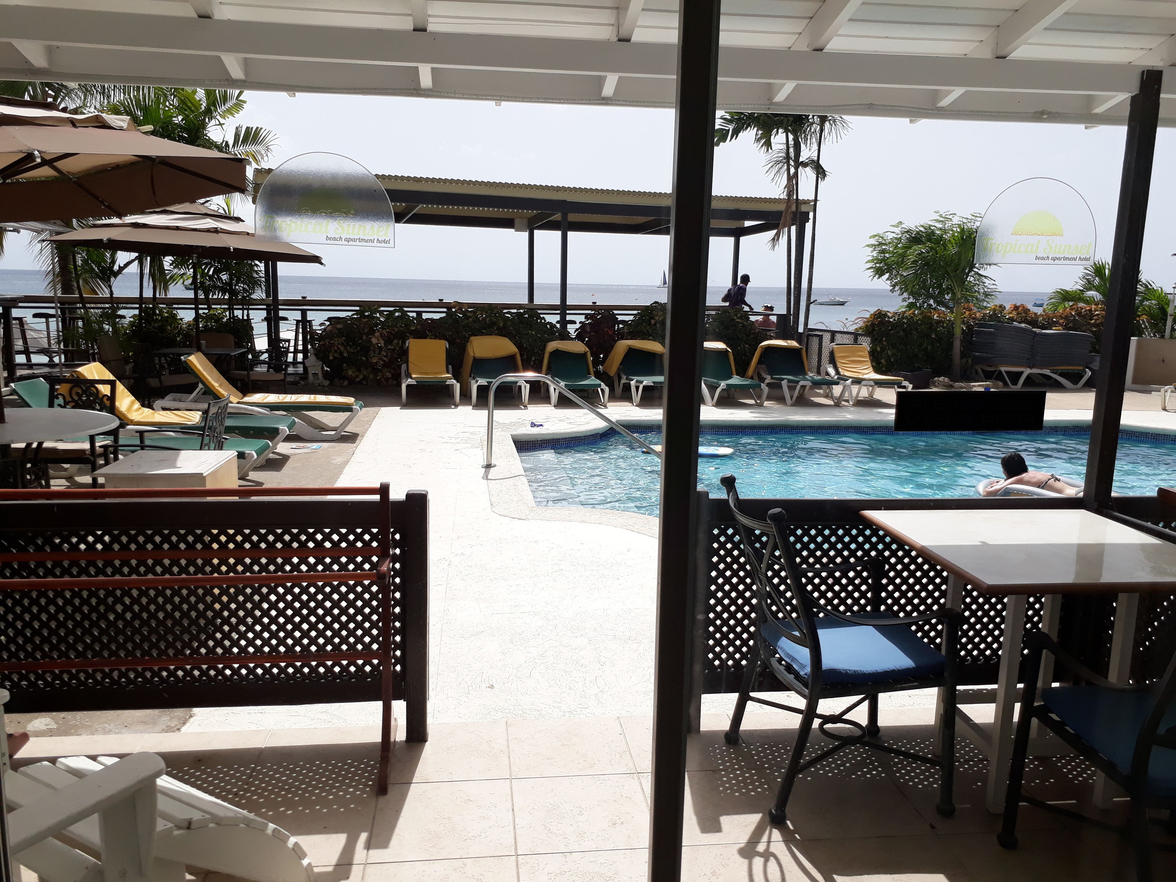 A poolside area with lounge chairs and a swimming pool, overlooking the sea.