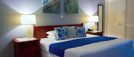 A hotel room with a large bed, two nightstands, a wooden headboard, and two wall-mounted paintings.