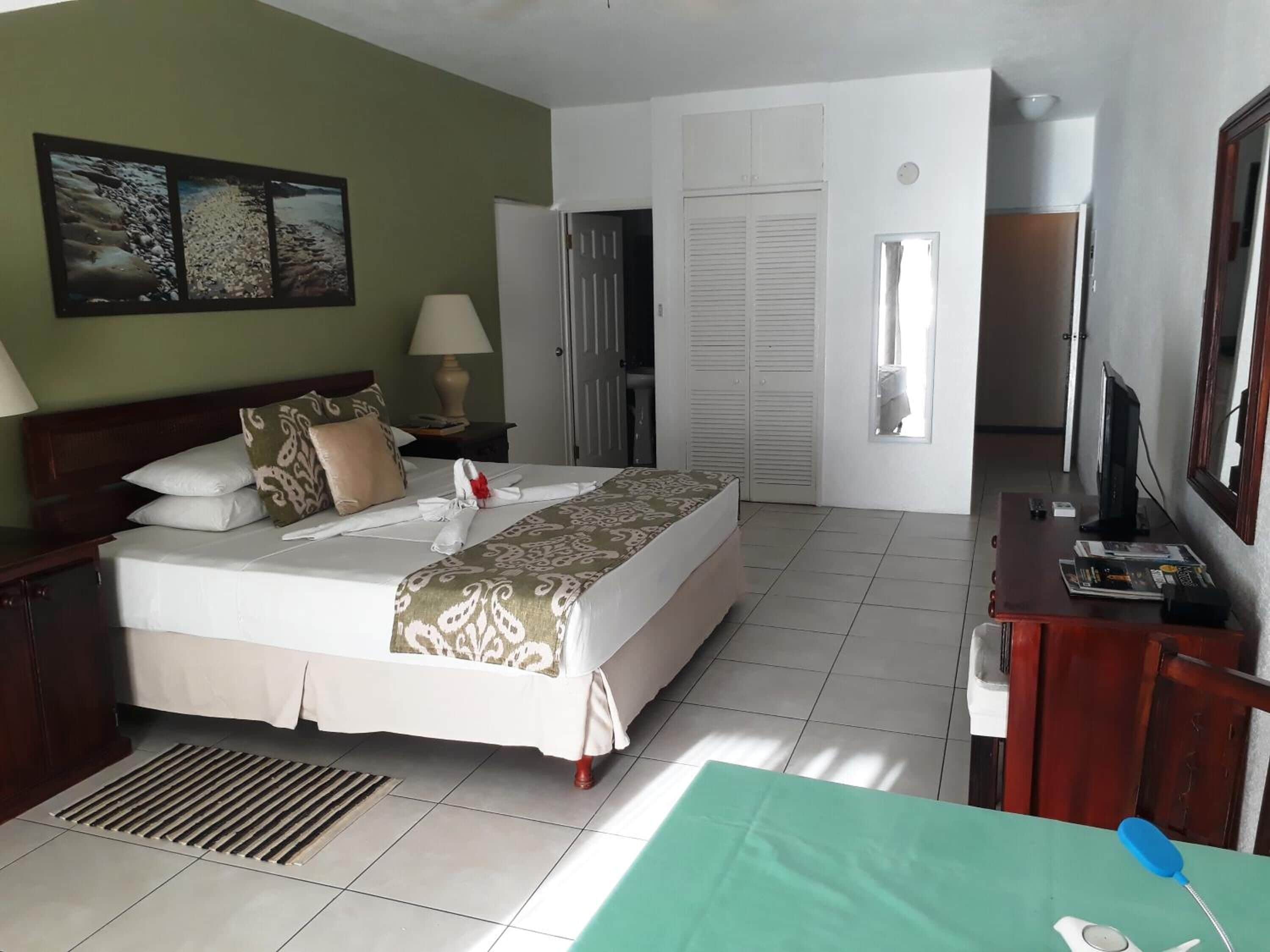 Una habitación de hotel ordenada con cama, escritorio, televisor y ventana.
