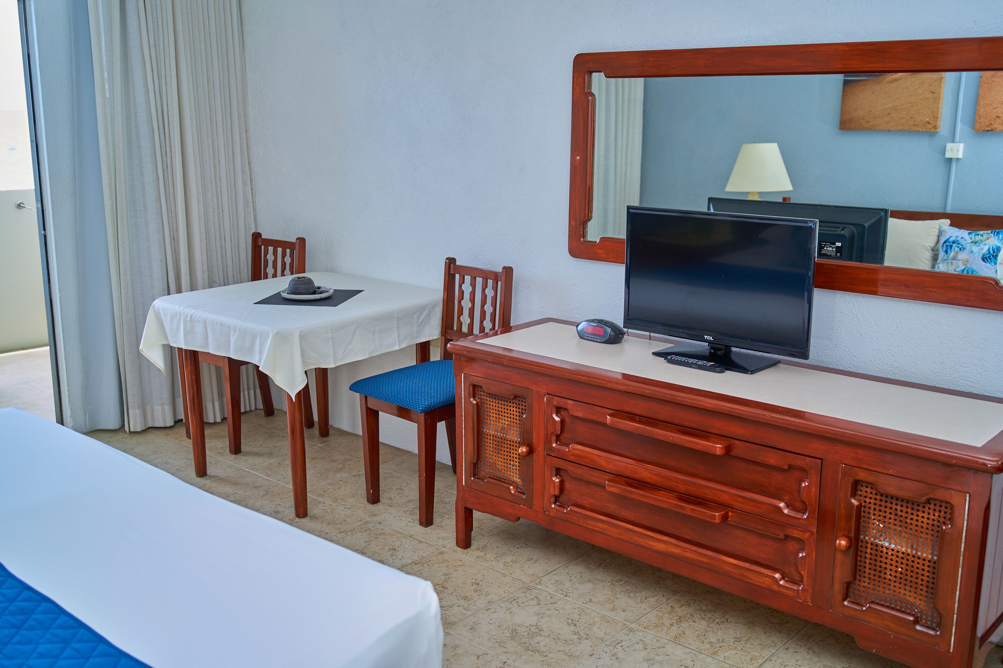 A hotel room with a bed, a desk with a television, and a chair.
