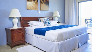 A hotel room with a large bed, two bedside tables with lamps, a window with curtains, and a view of the outside. - Tropical Sunset Beach Apartment Hotel (Holetown)