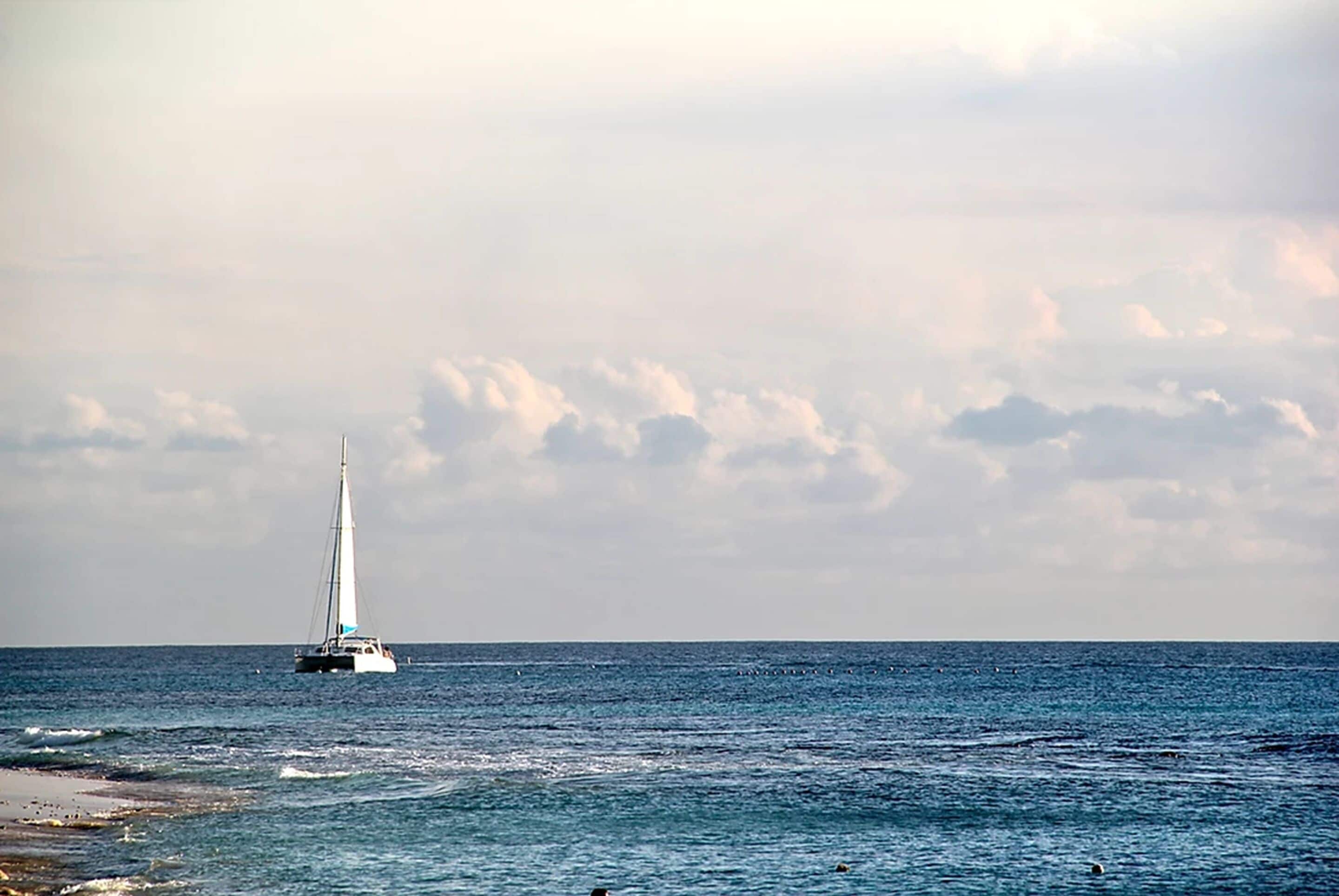 Una barca a vela su un mare calmo, con cielo nuvoloso.