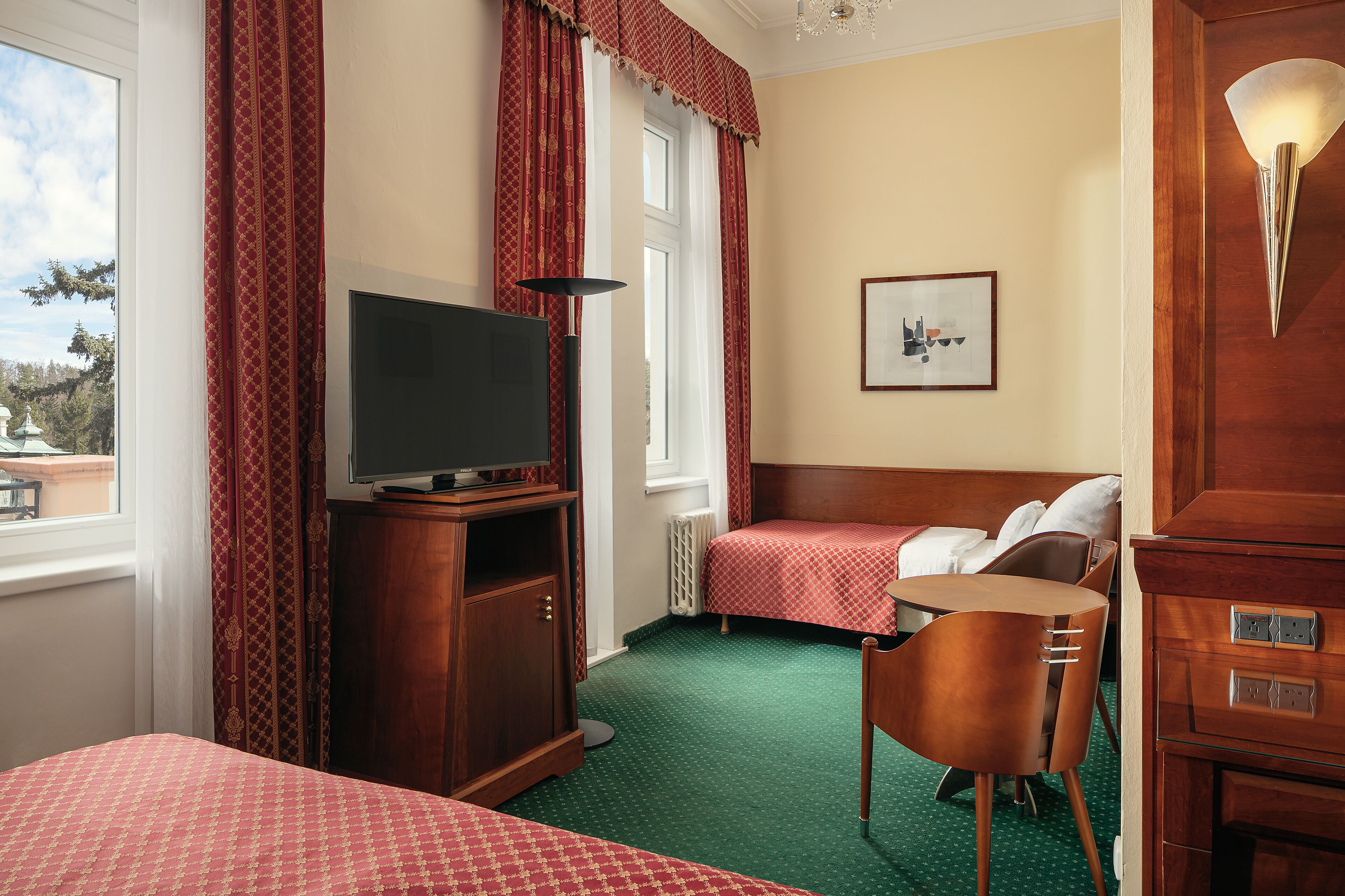 A hotel room with two beds, a television, a desk, and a chair.