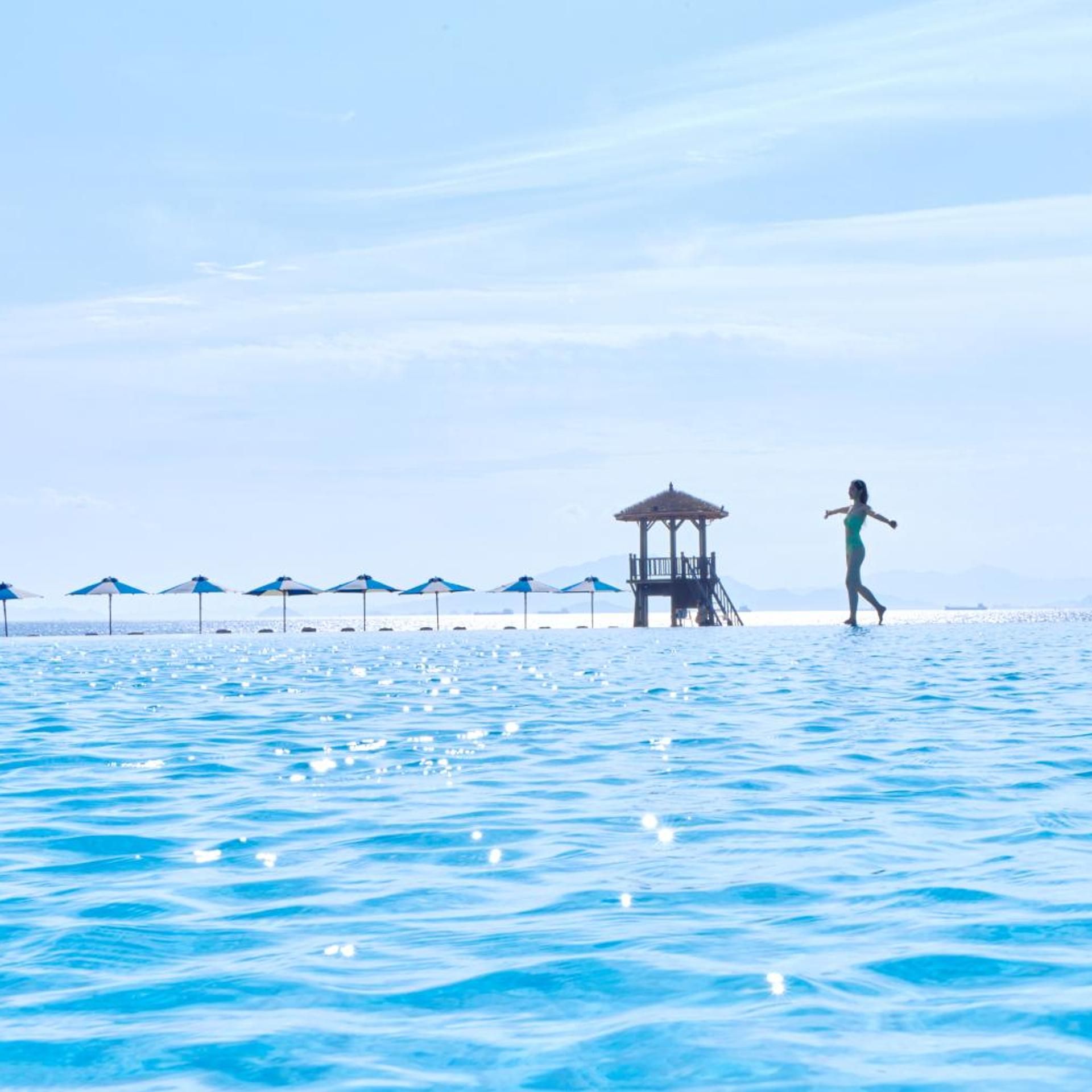 A beach with a lifeguard tower and umbrellas.