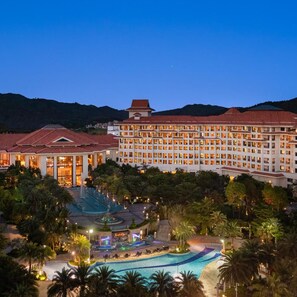 A large hotel with multiple floors, a swimming pool, and a landscaped area with palm trees. - Regal Palace Resort (Huizhou)