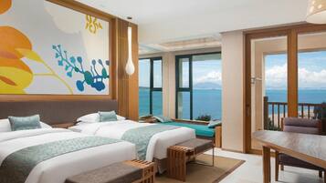 Habitación de hotel con dos camas, una mesa de comedor y vista al mar.