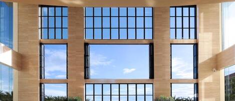 A modern hotel lobby with a large indoor pool, large windows, and seating areas.