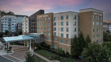 A multi-story hotel with a glass entrance and a parking lot.