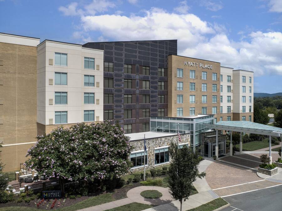 A multi-story hotel with a modern architectural design, featuring a glass entrance and a covered walkway.