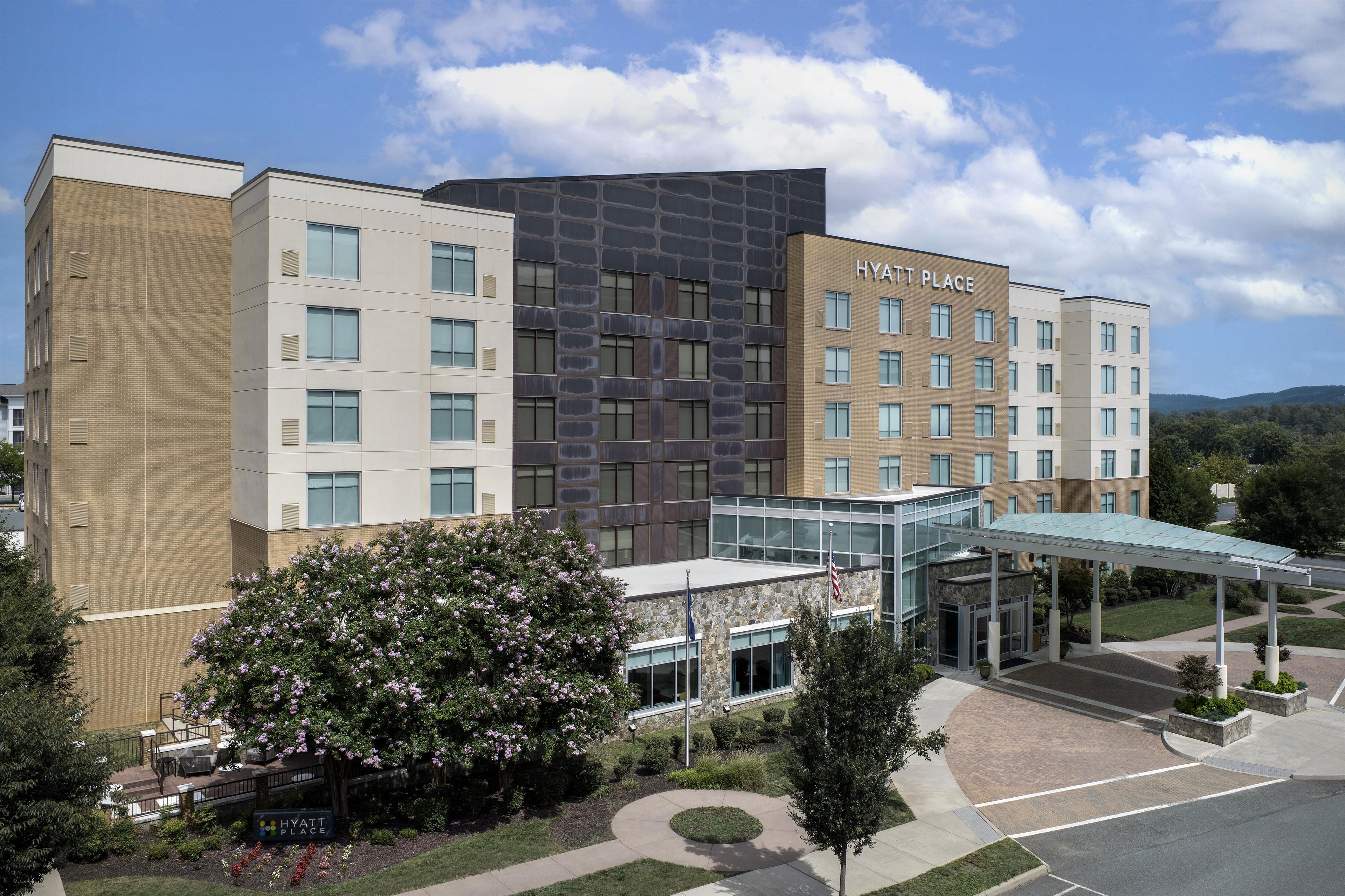A multi-story hotel with a modern architectural design, featuring a glass entrance and a covered walkway.