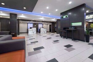 Un moderno vestíbulo de hotel con mostrador de recepción, zona de estar y mostrador de registro.