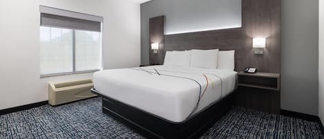 Una camera d'albergo moderna con un letto grande, un comodino con una lampada, un telefono a muro e una finestra con vista.