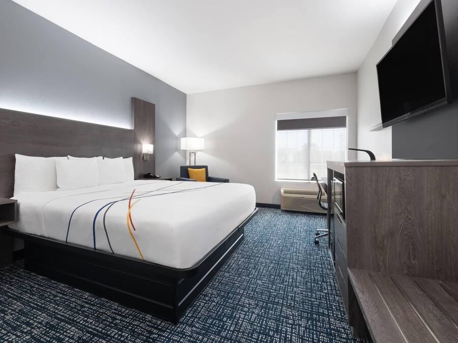 Ein Hotelzimmer mit einem großen Bett, Nachttischen, einem Schreibtisch, einem Sessel und einem Fernseher sowie einem Fenster.