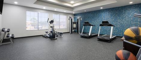Un gimnasio con cintas de correr, elípticas y pesas sueltas.