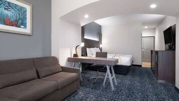 Habitación de hotel con sofá, escritorio, cama y televisión.