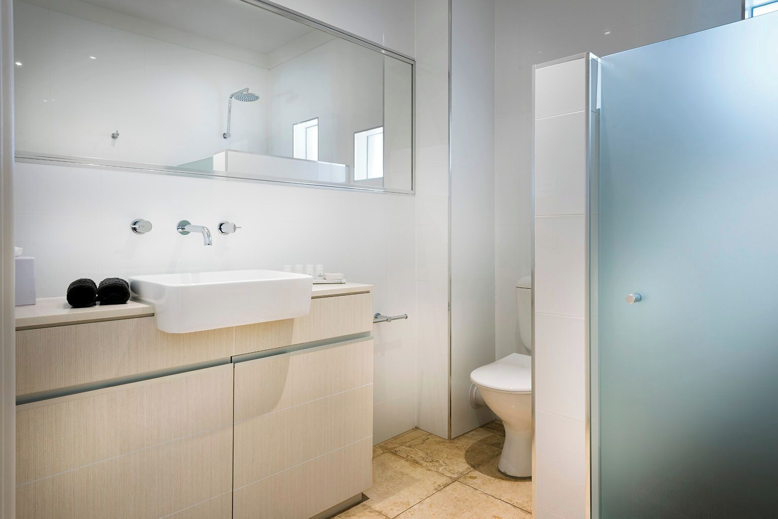 A modern bathroom with a white sink, mirror, and toilet.