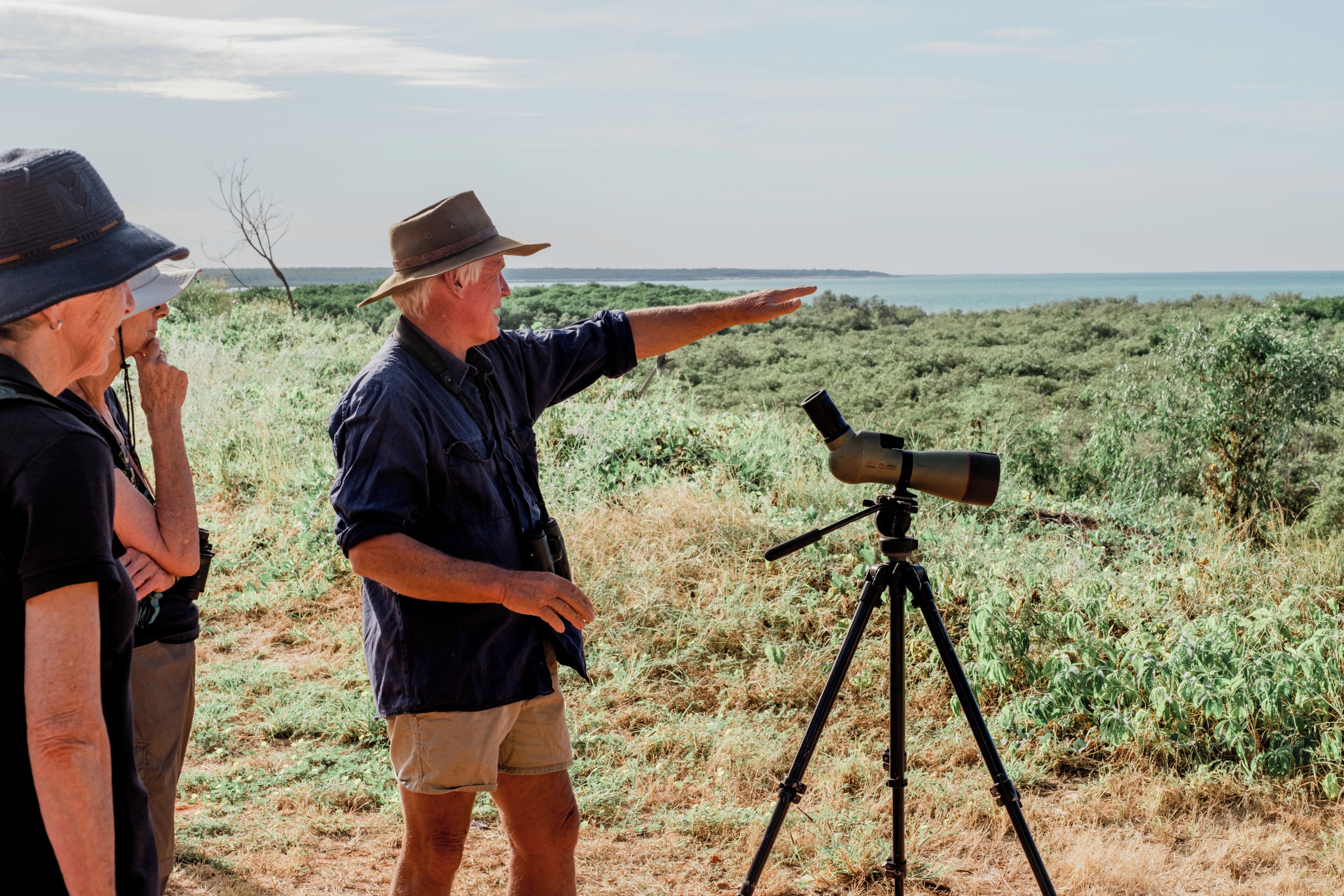 Una persona señala un telescopio sobre trípode en un entorno al aire libre.