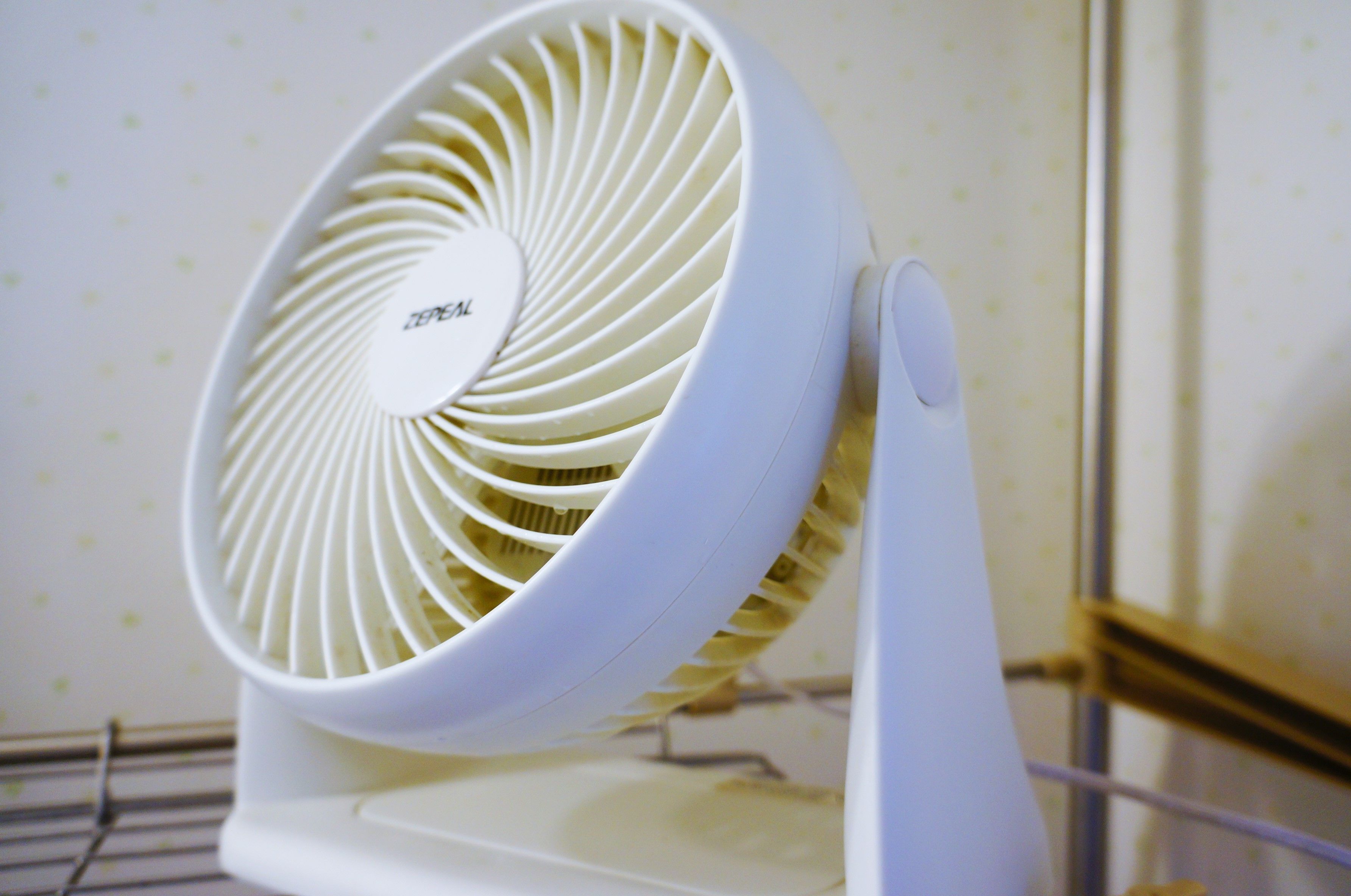 A white electric fan with a circular design and a control knob.