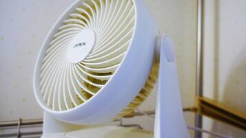 A white electric fan with a circular design and a control knob.