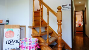 Un escalier en bois, avec une pancarte indiquant l’emplacement du comptoir d’enregistrement au premier étage.