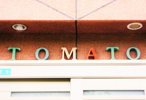 A building facade with the word "TOMATO" spelled out in large letters. - Osaka Tomato Hostel (Osaka)