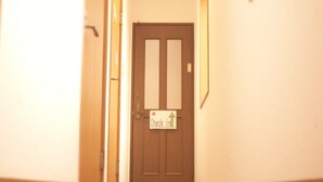 Un couloir au plancher de bois mène à une porte sur laquelle est apposée une pancarte indiquant « Enregistrement ».